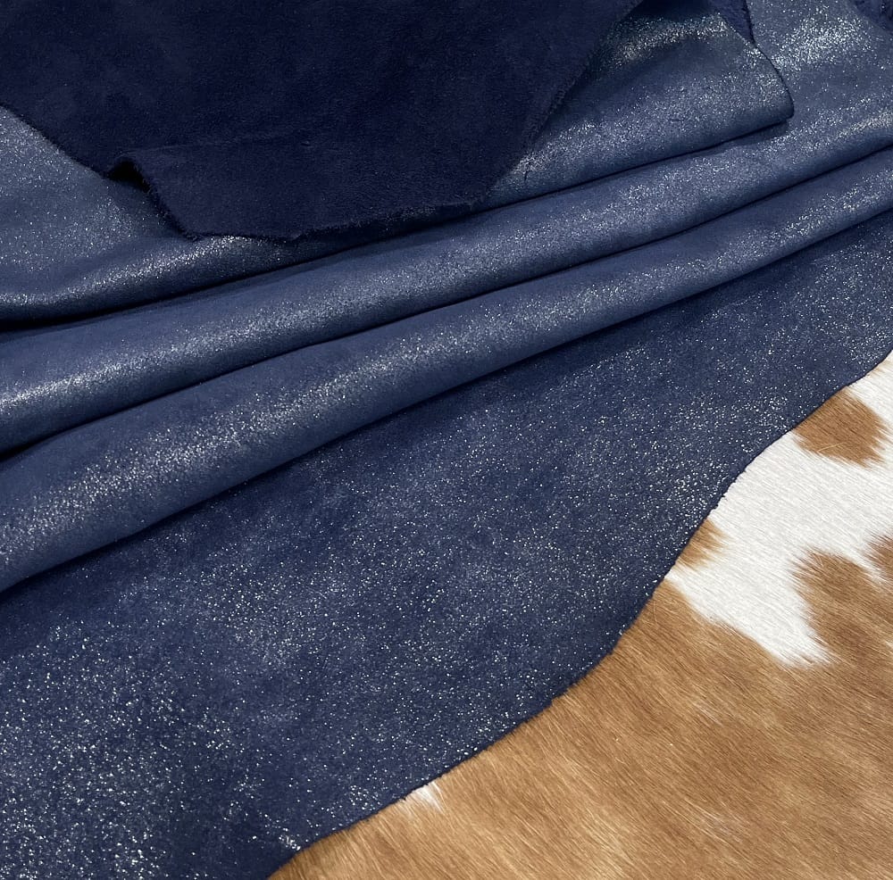 KP.Y.JELLY.M.INDIGO. (1) The Jelly Satin Suede Collection features high-quality leather products made from European cowhide treated with a glittery surface. The leather has a smooth suede texture in one direction and a coarser texture in the other, perfect for creating unique textures. Its shimmery yet subtle exterior creates a modern and chic look, ideal for footwear, garments, accessories, and more. The collection is made in Turkey using chrome tanning, which requires fewer chemicals and produces a more consistent color. It's free of harmful chemicals like PCP, Azo Pigments, Chrome VI, Formaldehyde, and APEO. This collection is perfect for those who value quality, style, and durability.