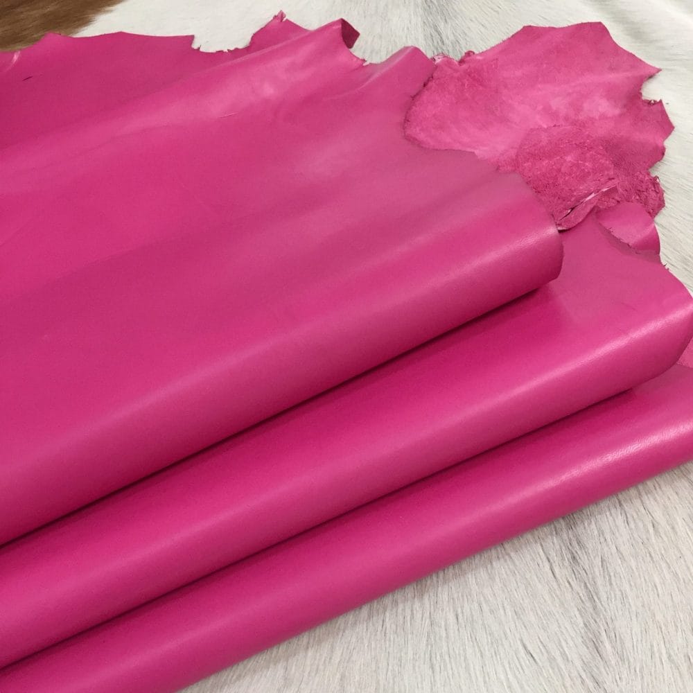 Avetco Inc Clearance Lambskin Bright Fuchsia (1) Economy Leather, Grade C, is a type of leather that might have some imperfections, but they do not affect its performance. Instead, these flaws give it a unique appearance. The leather's raw material is sourced from sheep or lamb, and it weighs 2 oz. with a thickness of 0.7-0.9 mm. The economy grade leather may have uneven shade tone, dark spots, stretch marks, scarring, scratches, or a few holes, but it is still suitable for various uses. The leather has a semi-gloss finish, and its soft-medium temper makes it pliable and easy to work with. An average hide size is 6-8 sq. ft., and it originates from Pakistan. You can use this type of leather for making accessories, arts and crafts, shoes, apparel, and more.