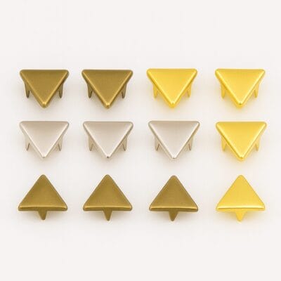 Three rows of 10mm triangle nailheads in Antique Brass, Nickel, and 14K Gold finishes, neatly arranged for color comparison – Avetco.