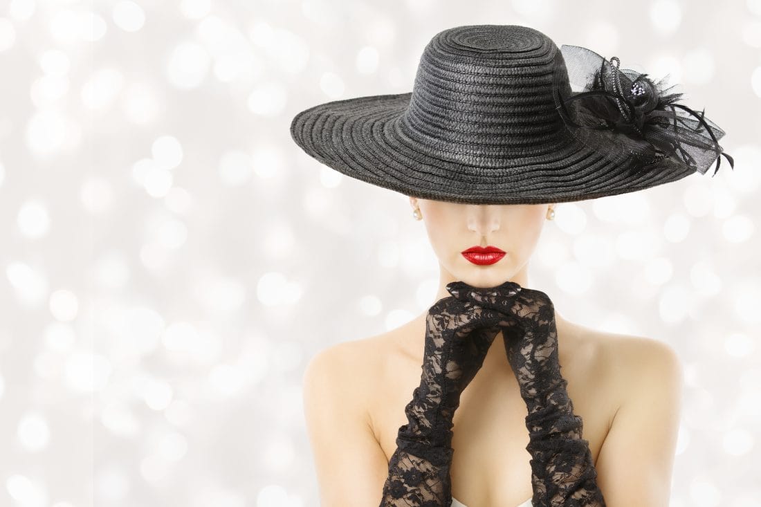 Elegant model in a black hat and lace gloves