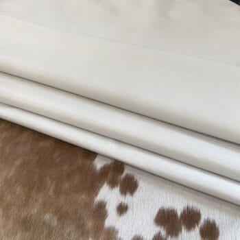 Bone full grain pig leather, tannery run grade, folded on a cowhide rug