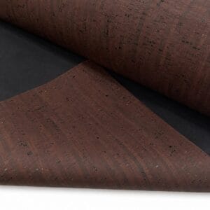 Close-up of dark brown cork sheets rolled on a black background, showing a speckled textured surface.