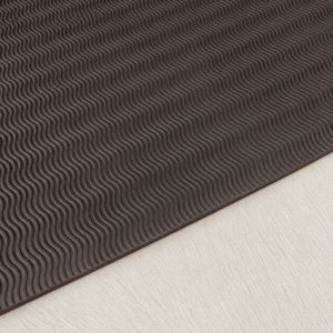 brown wavy tread sheet Brown textured mat with repeating wavy grooves on a light wooden floor edge