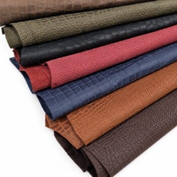 escape alligo cow leather crocco belly embossed Rolled leather fabric swatches in brown, tan, red, blue, and gray with a crocodile skin pattern laid in stacked layers