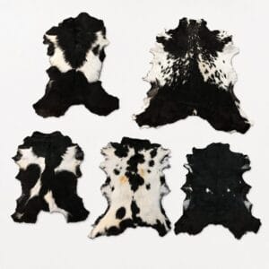 espresso goat hair on Six black-and-white cowhide patches laid out on a white surface in two rows of three.