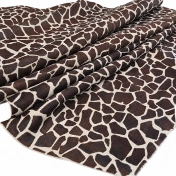 hair on cowhide giraffe print Fabric with a giraffe-print pattern in brown and cream, rolled and laid out in folds