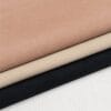 main Stack of fabric swatches in pink-beige, beige, tan, and black on a light wooden surface.