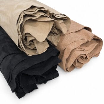 Rolled bundles of suede-like leather scraps in black, beige, and tan laid together on a white background.
