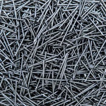 Close-up of a chaotic pile of shiny steel nails overlapping each other.
