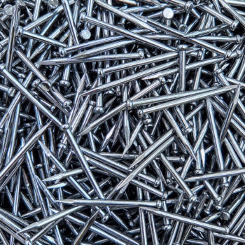 Pile of shiny silver nails densely packed, zinc-coated and pointed with rounded heads.
