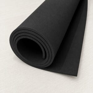 Rolled black yoga mat on a light wood floor.