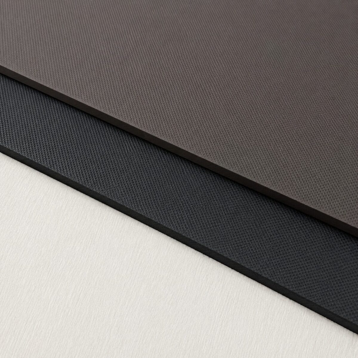 Eva Brown and Black Diagonal close-up of stacked textured leather/fabric swatches in brown, black, navy, and beige colors with subtle grain pattern.