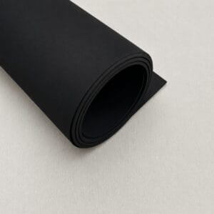 Rolled black foam sheet on a light background.**