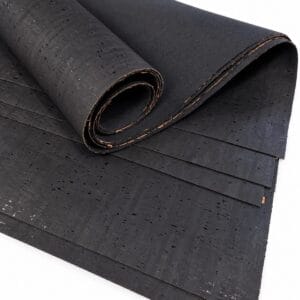 Rolled black cork sheet with a speckled texture, partially unrolled to show layers.