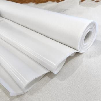 Rolled white vinyl fabric or wallpaper on a light surface, with the edge curled up to show layers of material
