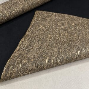 natural cork fabric meadow Rolled cork-textured fabric with a black underside, featuring a speckled beige-gold pattern as seen on an upholstery roll.
