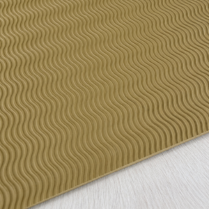 natural wavy tread sheet product photo Close-up of a gold-toned rug or mat with repeating wavy ridges on a light floor surface.
