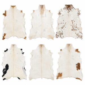 natural white goat hair on Six cowhide rugs laid flat, showing a range of brown and black patches on white fur on a white background.