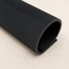 PR503.fine line Black textured rubber mat rolled into a hollow cylinder on a light wooden surface