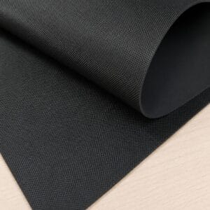pyramid black large sheet Rolled-up black textured exercise mat on a light wooden surface, showing its grip pattern and edge curling up.