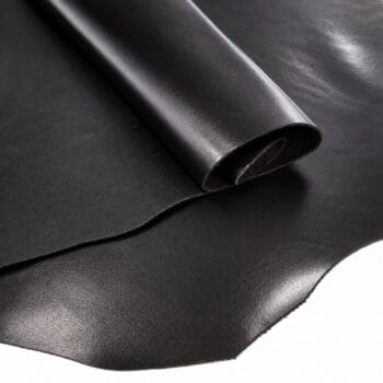 Rolled black leather sheet on a smooth surface, showing its texture and edge.