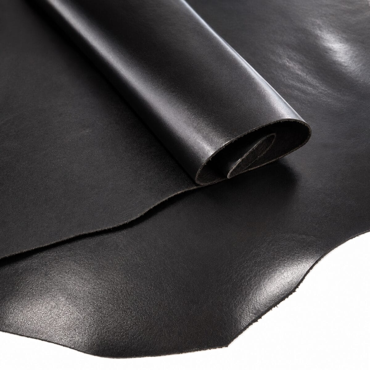 semiveg aniline cow leather oz black Rolled black leather sheet on a smooth surface, showing its texture and edge.