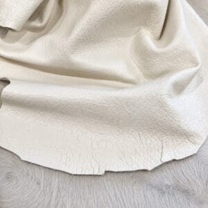 Cream leather fabric draped over a soft gray fur surface, showing natural grain and folds.