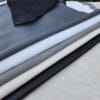 SL-115 stretch lamb Assorted SL-115 Stretch Lamb leather hides in black, light gray, gray, ivory, and navy blue displayed in a layered arrangement.