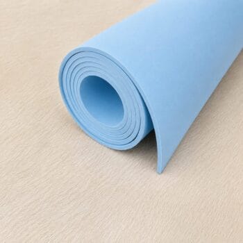 Rolled blue yoga mat resting on a light wooden floor