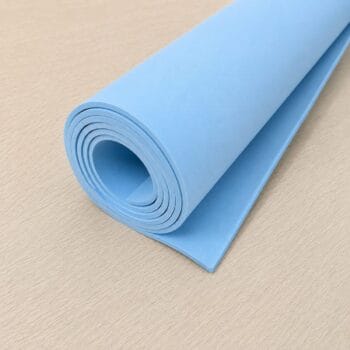 Rolled blue yoga mat on a light wooden floor
