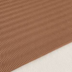 tan wavy tread sheet Close-up of a brown rubber mat with a wavy, ribbed pattern resting on a light wood floor edge visible at the bottom.