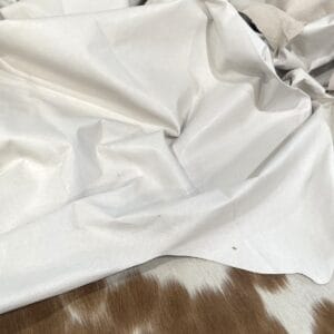 White pig leather draped, showing natural grain marks White pig leather draped, showing natural grain marks – tannery run